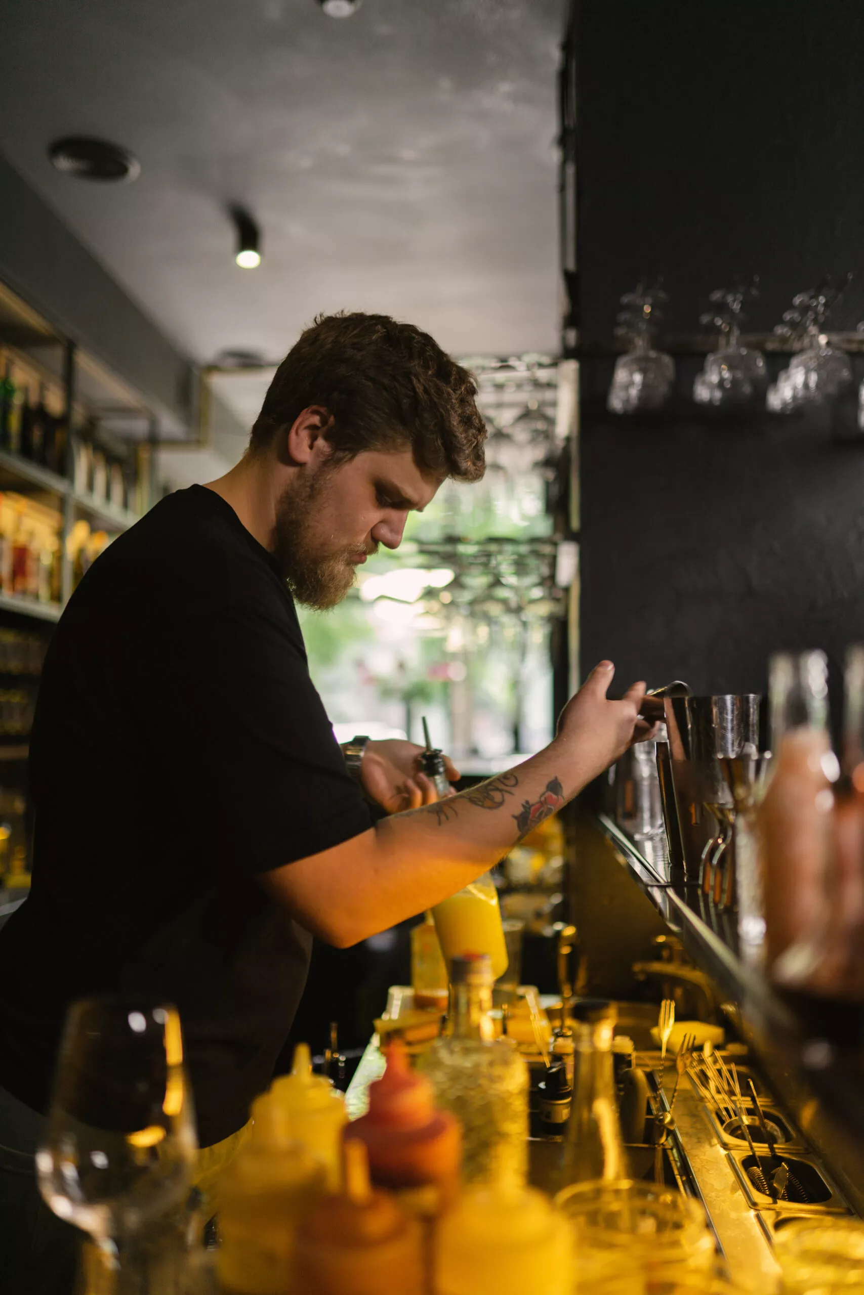 Barista manipola gli ingredienti per preparare un cocktail per il cliente. Master class sulla preparazione di bevande artigianali da parte di un barman professionista