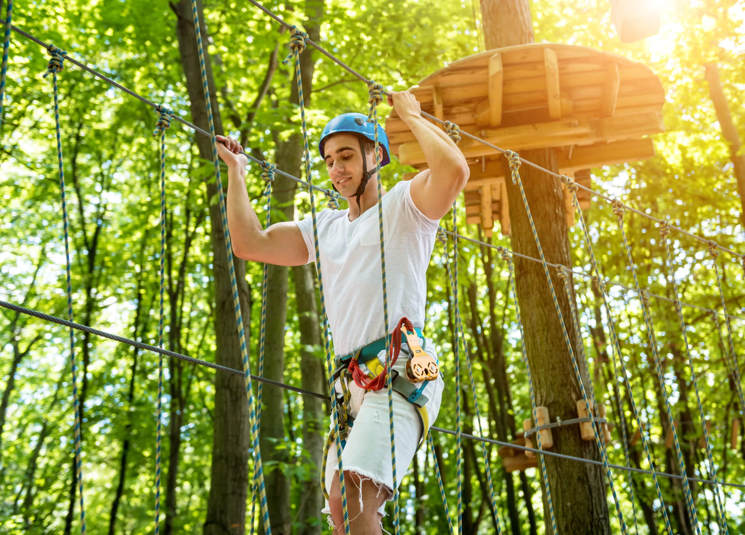 Giovane uomo in un parco avventura. Attrezzatura per l'arrampicata.